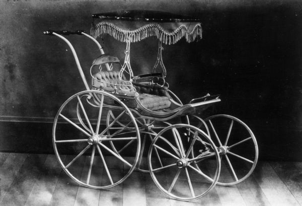 Children's carriage with small tasseled canopy produced at children's carriage factory.