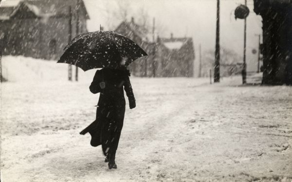 Winter scene with a pedestrian holding an umbrella during a snowstorm, Milwaukee, Wisconsin.