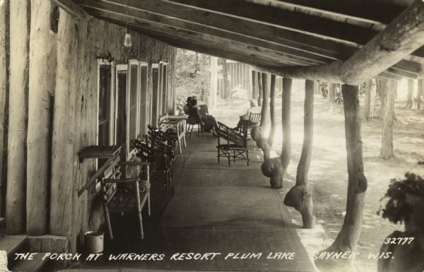 View along the porch at Warner's Resort. The porch roof is supported by large rustic tree trunks or branches. Caption reads: "The Porch at Warner's Resort, Plum Lake, Sayner, Wis."