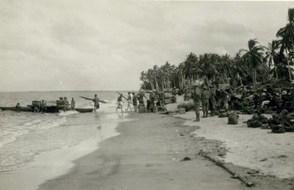 Lacking other equipment on the beach, native canoes were pressed into service to transfer equipment to larger boats.