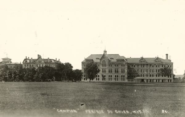 View across grounds towards Campion College. Caption at bottom reads: "'Campion' Prairie du Chien, Wis."