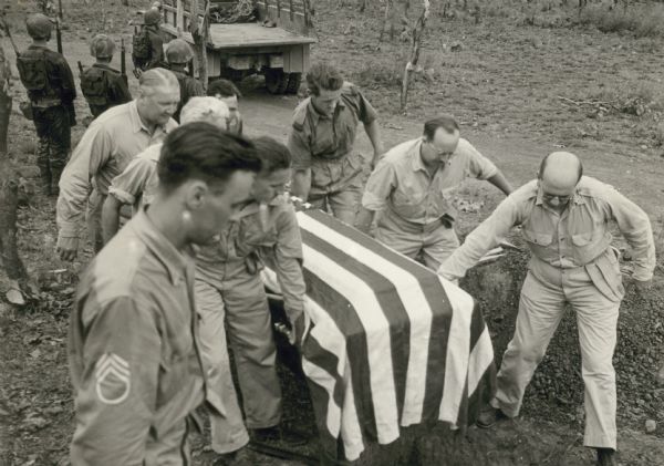 War correspondents carry the flag-draped casket containing the body of Byron Darnton, the first casualty of their group; Bomana Military Cemetery, Port Moresby, New Guinea. Darnton was a reporter for the New York Times.