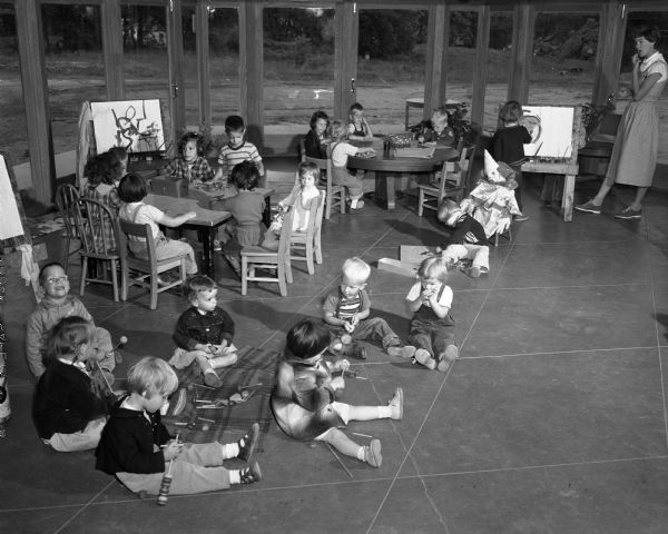 Children sitting on the floor and working on art projects at tables in the nursery school at the First Unitarian Society Meeting House. The building was designed by Frank Lloyd Wright. This space was originally known as the West Living Room, as Wright intended it to be part of the parsonage.