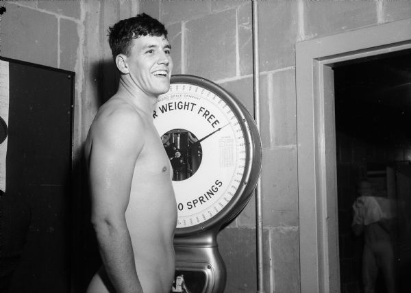 University of Wisconsin football player Jack Mead standing on a scale for weigh-in.  Mead went on to participate in the 1945 Pro Football College Draft and was selected by the Giants in the 10th round of that draft.