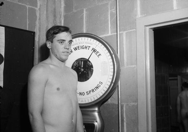 University of Wisconsin football player Nick Holmes standing on a scale for weigh-in.