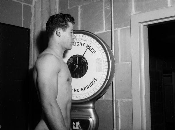 University of Wisconsin football player Clarence Esser standing on a scale for weigh-in.