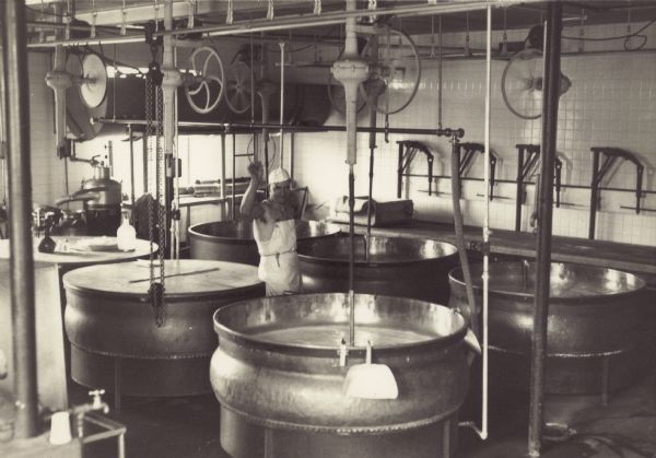Ernest Albert Hilfiker (1905-1993) poses with copper kettles in the making room of the Tuscobia cheese factory.