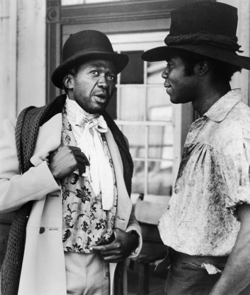 Actors Ben Vereen (left), as Chicken George, and Georg Stanford Brown as Tom, in a television still from the popular 1977 television mini-series "Roots". The production was based on the semi-fictionalized genealogical research by Alex Haley on his slave ancestors.