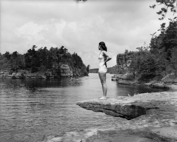 Woman in bathing suit posing on ledge. High Rock is in the background.