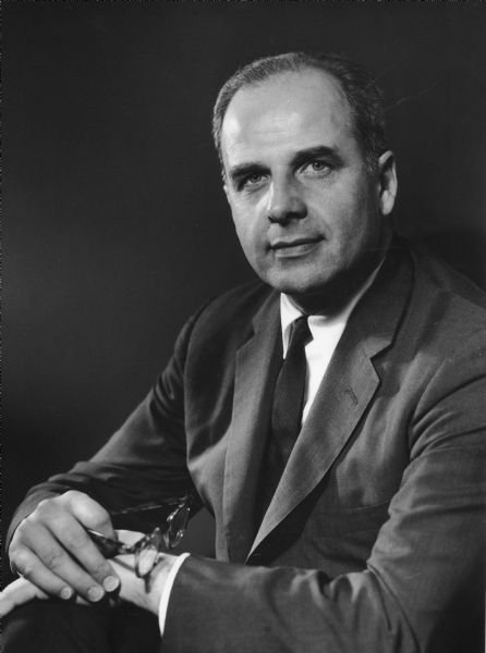 Studio portrait of Gaylord Nelson. He is holding a pair of eyeglasses in his right hand.