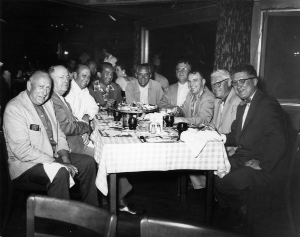 Men seated at a table at the Holiday Inn. From left to right are Harvey Abraham, Frank Panzer, Mac Arthur, Ed Murrow, Ned Hoebel, Nitschke, Maratz, Sphrecher, and Travis.