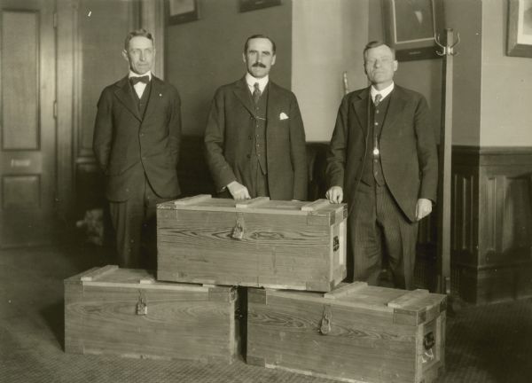 Clerk E.J. Walden, Secretary John S. Donald and Assistant Secretary L.B. Nagler pose with three wooden boxes full of election ballots in the Secretary of State offices.