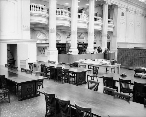 Historical Society Library Reading Room and the Visitors Gallery after their modernization during the mid-1950s.  Prominent among the visible changes are a new circulation/reference desk; microfilm cubicles, and the installation of acoustical tile in the ceiling of the Visitors Gallery.