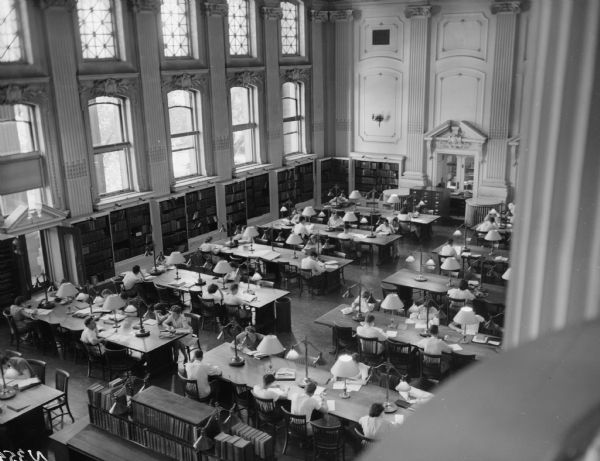 A view of the Library Reading Room from the Visitors Gallery in 1948, showing crowded conditions.  Cosmetic changes to the appearance of the room included additional table lamps for supplemental lighting and more bookshelves around the perimeter.
