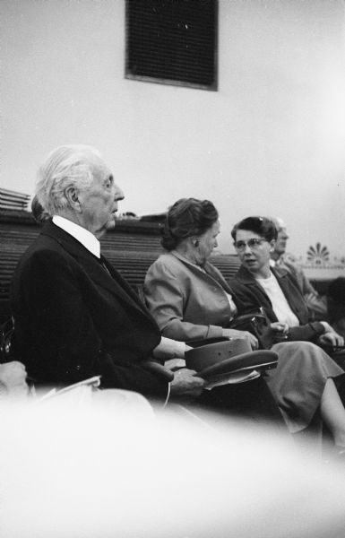 Architect Frank Lloyd Wright seated at a hearing on the Frank Lloyd Wright Foundation at the Wisconsin State Capitol in the Education and Transportation Offices, room 314 NW. Wright testified before the Assembly Taxation Committee in favor of a bill granting tax-exempt status to Taliesin as a non-profit education institution.