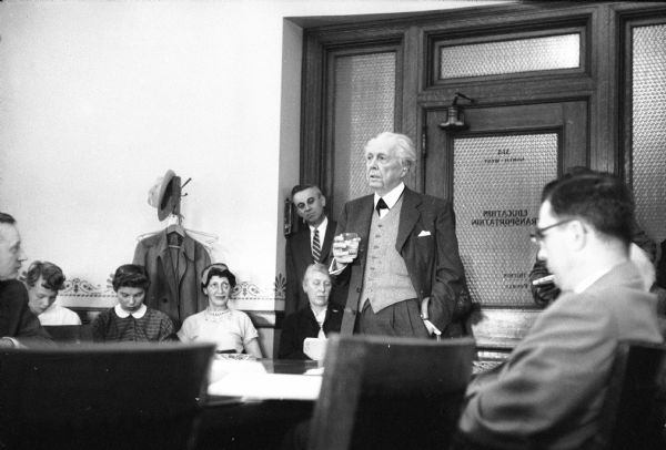 Architect Frank Lloyd Wright speaking at a hearing at the Wisconsin State Capitol. The hearing was held in the Education and Transportation Offices, room 314 NW, at the Capitol. Wright testified before the Assembly Taxation Committee in favor of a bill granting tax-exempt status to Taliesin as a non-profit education institution.