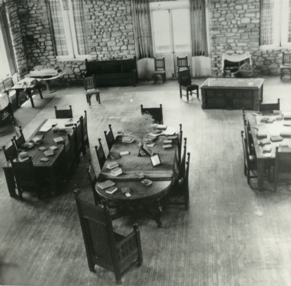 View from balcony of the interior of the Chester Thordarson boathouse with several tables, upon which are numerous books.
