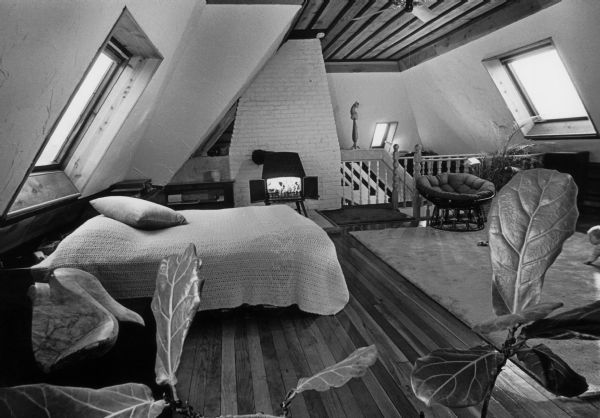 Interior view of an attic bedroom with skylights and a television.