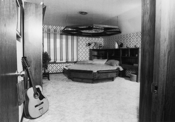 Bedroom featuring an octagonal bed with a guitar in the foreground.