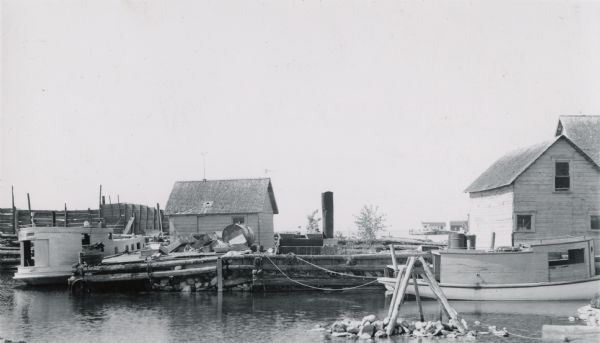 Dock with two steamboats and fishing implements in harbor.