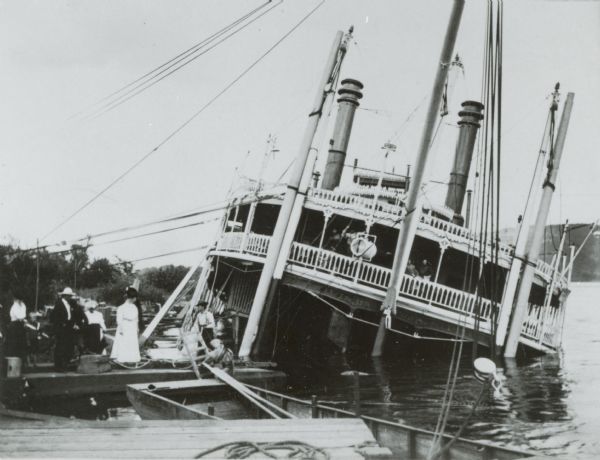 Bow of the sidewheel packet, "Quincy," sunk in 1906. People are standing on temporary pier beside her. Later raised and renamed the "J.S."