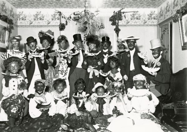 Group of Caucasian individuals dressed up as African Americans, in blackface and eating watermelon.