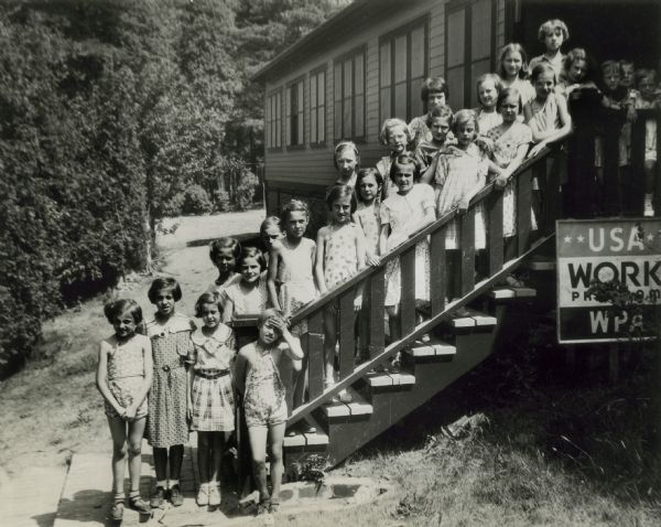 Children assemble on the stairs of a WPA built cabin.