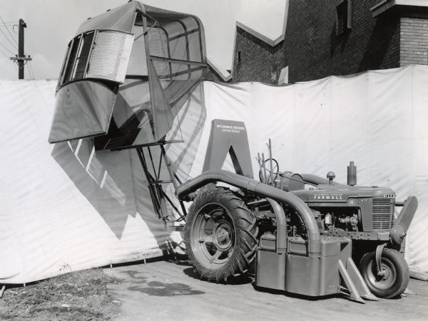 Engineering photograph of an experimental 2-row cotton picker mounted on a Farmall "H" tractor.  Its storage basket is open to simulate the release of harvested cotton.