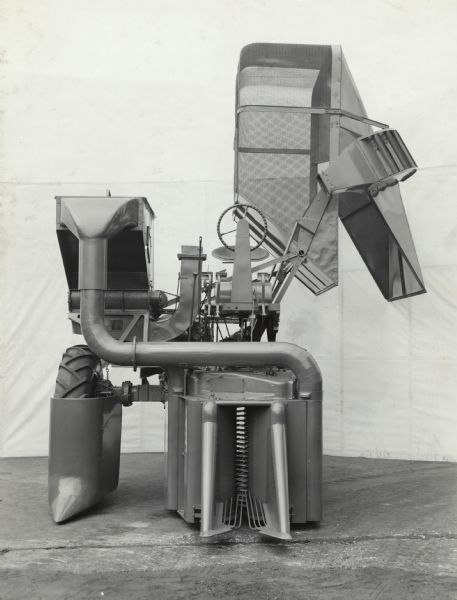 Engineering photograph of an experimental cotton harvester [picker] with its storage basket rotated outwards as if to release the picked cotton(?).