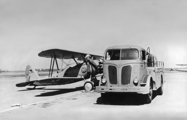 International D-500 used as a fuel truck. A man appears to be fueling a U.S. Air Force biplane with a "Long Beach" decal on its side.