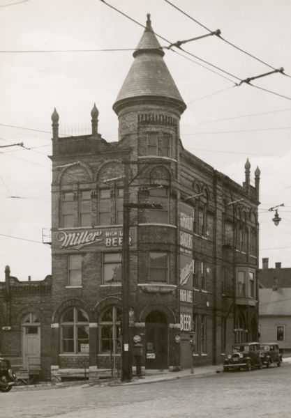 Exterior view of the Humboldt Gardens Hotel at the southwest corner of North and Humboldt Avenues. There are large Miller Beer advertisements on the side of the building.