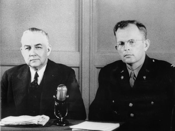 Byron Price and W. Preston Corderman seated at a table behind a microphone.