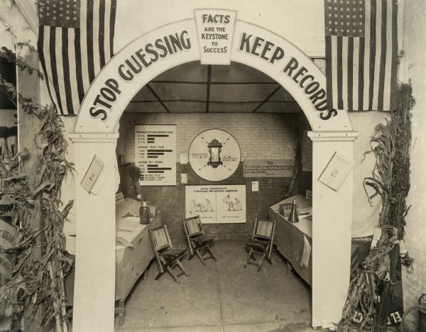 An agricultural exposition display relating to farm management, shown jointly by the University of Wisconsin College of Agriculture and the U.S. Department of Agriculture. The display reads, "Stop guessing, keep records, facts are the keystone to success".