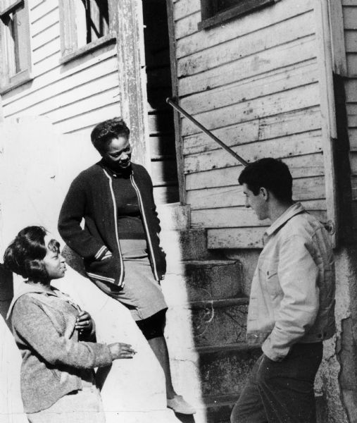 Tom Hayden talking to two African-American women on house steps. The woman in the center is Terry Jefferson (as identified by Hayden).