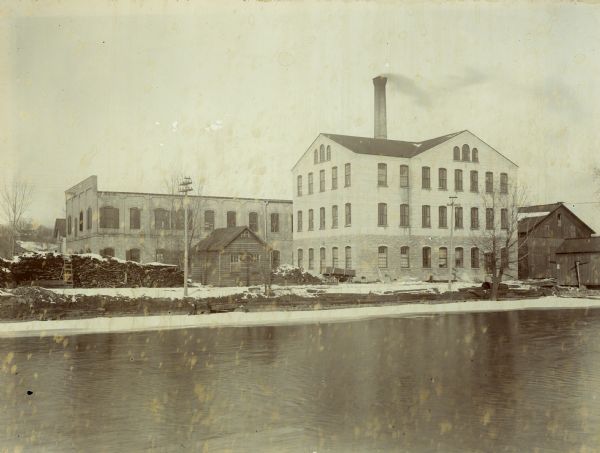 View of the Appleton Woolen Mills from the south, circa 1895. The three-story building in the right front was constructed in 1893.  The long, two-story building behind it was built after the fire of 1881. A corner of the office building roof is visible at the very left of the photograph, behind the 1881 factory.