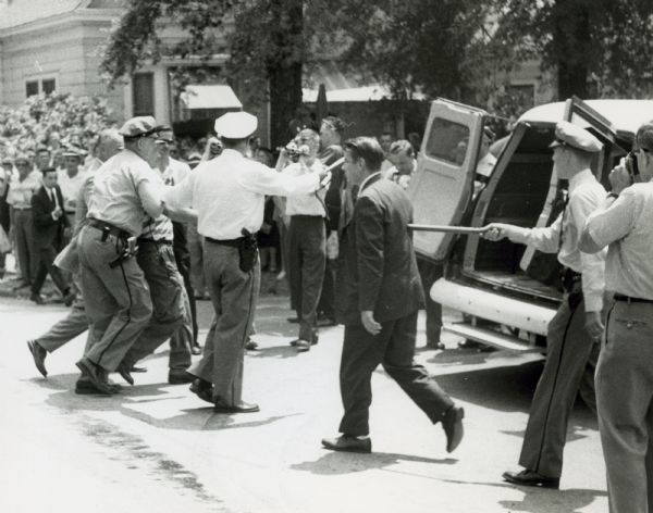 Mob violence during the integration crisis in Little Rock. Probably taken between September 20th, when Governor Faubus withdrew the National Guard and September 25, when President Eisenhower federalized the Arkansas Guard.  The Little Rock police, who had been left to control the crowd during this period, had been challenged by the angry crowd, and here they are leading some of the crowd to the police van.