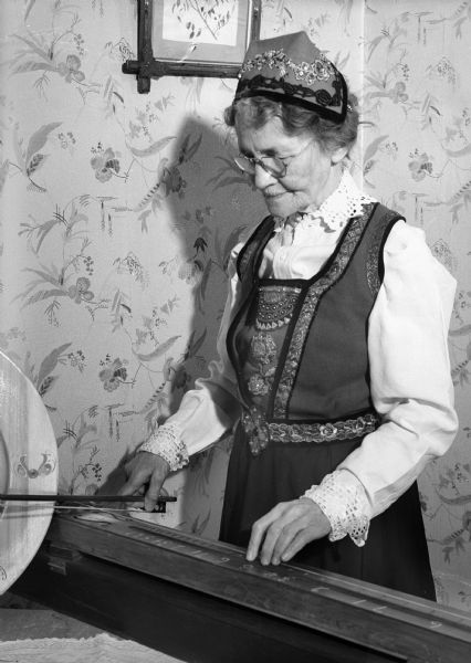 Woman in Norwegian dress playing the monochord.