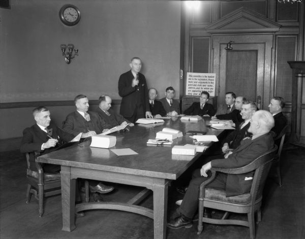 Assembly members seated around a table at a committee meeting.