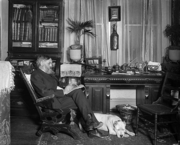 Rasmus B. Anderson seated in his study with his dog at his feet.