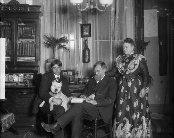 Rasmus B. Anderson, his wife, and son in Anderson's study. Anderson's son holds the family dog.