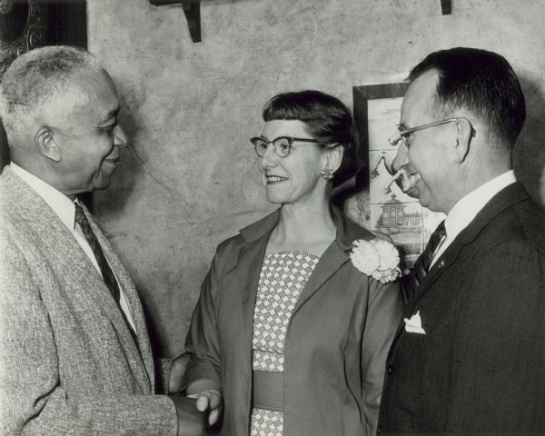 William Kelley on left shaking the hand of Helen Brown as Art Schmidt of Schlitz Brewing Company looks on.