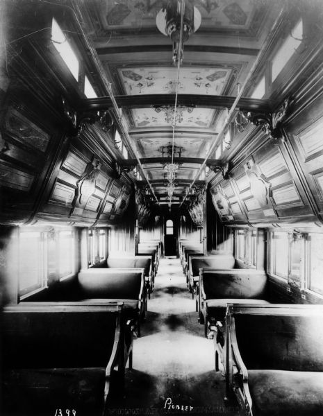 Interior view of the Pullman sleeping car "Pioneer," which is arranged for daytime use, and showing the richly ornamented paneling and painted ceiling. This car was used on the Chicago, Milwaukee, and St. Paul Railroad.