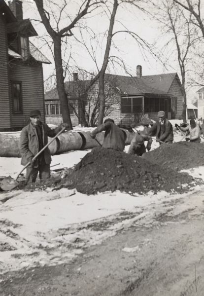 As part of a Wisconsin unemployment project, workmen dig a sewer trench by hand for the city of Spooner.