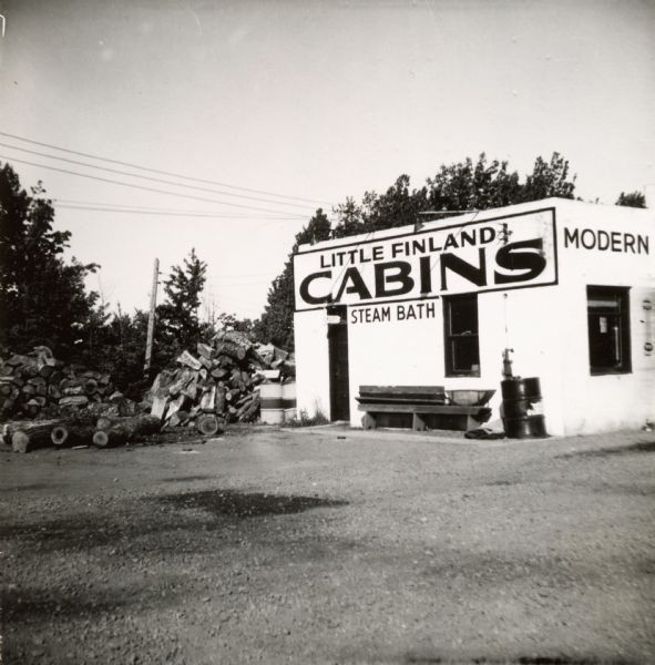 Exterior view of Little Finland Cabins featuring a steam bath. There is a large woodpile at one side of the building.