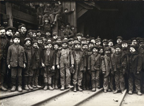 Group of boys in work clothes assembled outside a mine.