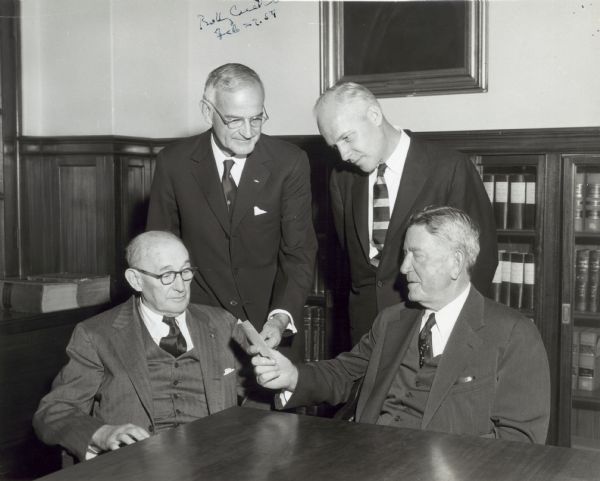 Seated from left to right, are Arthur W. Page and Eugene Holman. Standing behind them, left to right, are Gerie Cutler and Mr. Rhoads.
