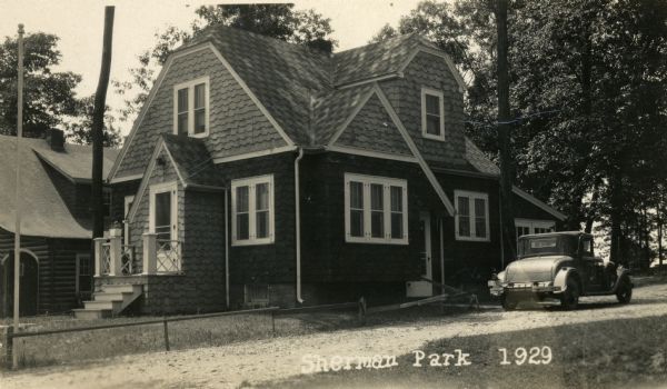 Exterior of the shingle-sided house at 1419 Sherman Avenue, in Sherman Park. Built by Willard Droster, with a car in the driveway.