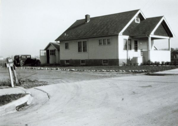 Exterior of the house at 2702 E. Johnson Street shortly after construction. An automobile is parked in the driveway. The house was built by Willard Droster.