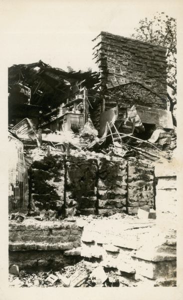 Postcard photograph of the remains of the living room at Taliesin after the fire destroyed most of the living quarters. The living room fireplace, and a portion of the kitchen remain standing. Taliesin is located in the vicinity of Spring Green, Wisconsin.
