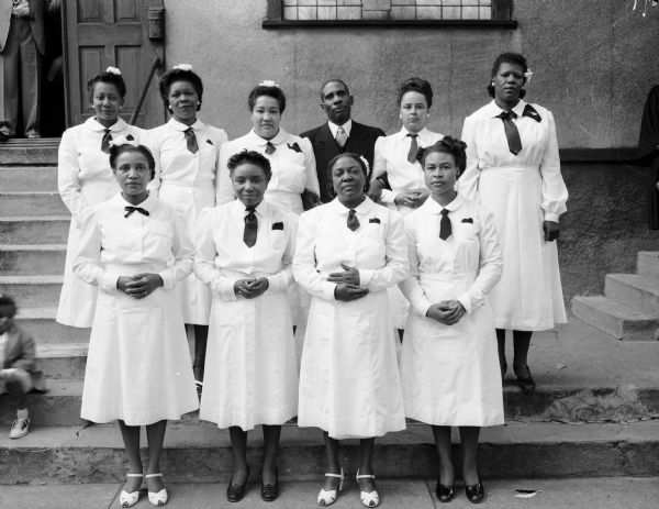 Group portrait of nine African-American women and Rev. Cunningham (?) standing in front of Mt. Zion Baptist Church, 548 West Johnson Street.